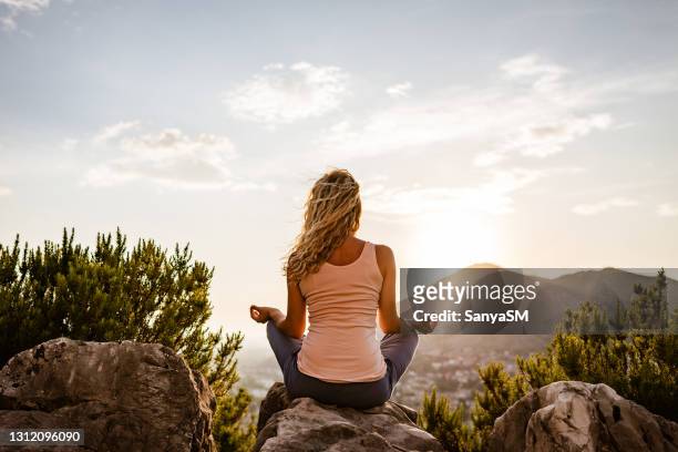 young woman preforms yoga in mountains at sunset - back shot position stock pictures, royalty-free photos & images