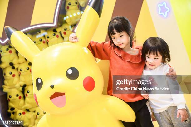 Children pose for a photo with a Pikachu toy during a Pokemon-themed activity at a shopping centre on April 11, 2021 in Fuzhou, Fujian Province of...