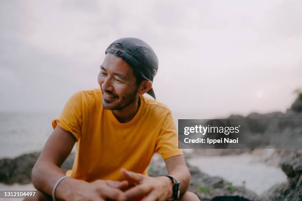 japanese man sitting on beach at dusk - impulsiv stock-fotos und bilder