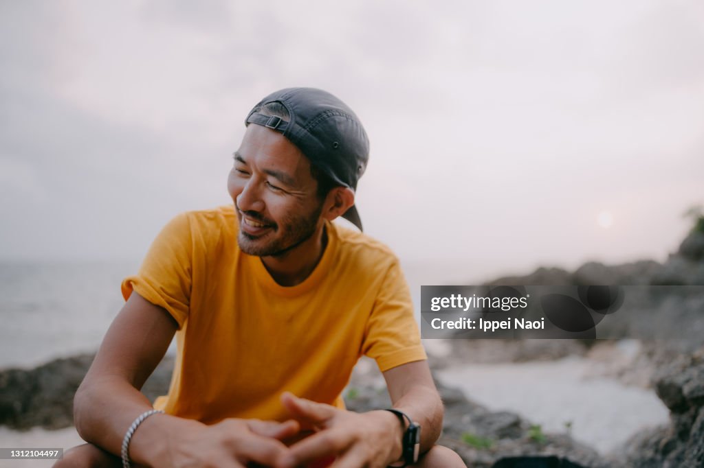 Japanese man sitting on beach at dusk