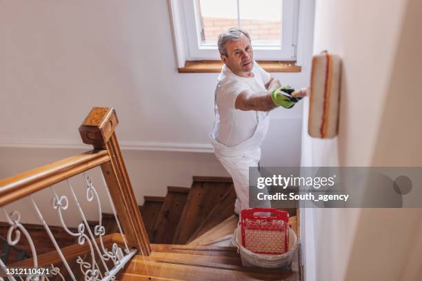 male painter painting a wall - white paint roller stock pictures, royalty-free photos & images