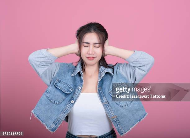 confused woman puts her hands on the head, isolated on pink,woman put her hand on her ears - ohrenschmerzen stock-fotos und bilder