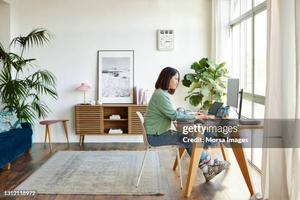 businesswoman working on computer at home office - femme assise bureau photos et images de collection