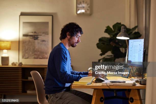 male entrepreneur using computer at table - télétravail photos et images de collection