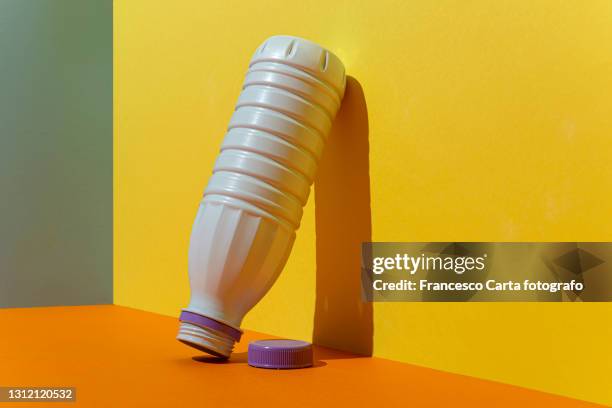 milk bottle upside down leaning against a multicolored background - yellow milk stock-fotos und bilder