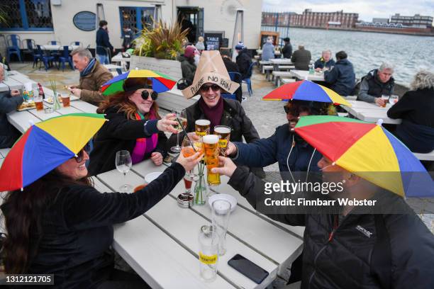 Members of the public enjoy a drink outside at The Still & West pub at Spice Island on April 12, 2021 in Portsmouth, England. England has taken a...