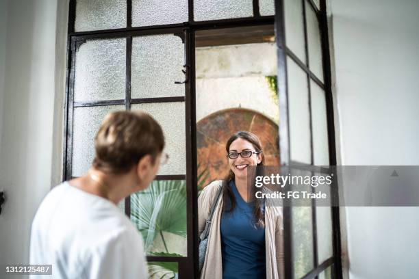 home caregiver arriving at patient's house - family smiling at front door stock pictures, royalty-free photos & images