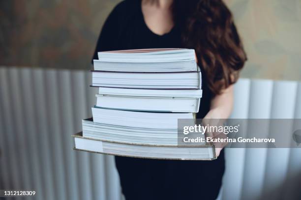 a woman is holding a large stack of books or magazines - bulk test stock pictures, royalty-free photos & images