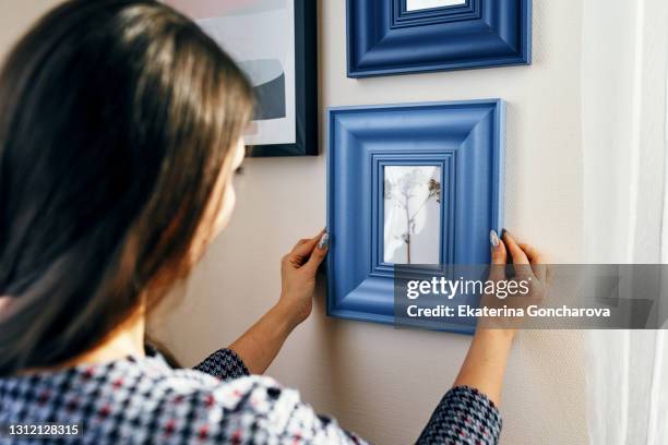 close-up young woman apartment, hangs frames on the walls. - decorating fotografías e imágenes de stock