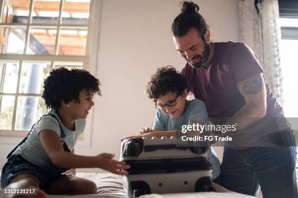 bambini che aiutano il padre a fare le valigie a casa - suitcase close foto e immagini stock