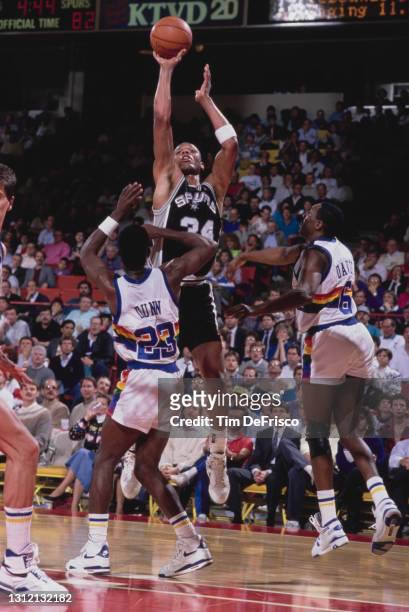 Terry Cummings, Power Forward and Small Forward for the San Antonio Spurs attempts a one handed lay up shot over Walter Davis and T.R. Dunn of the...