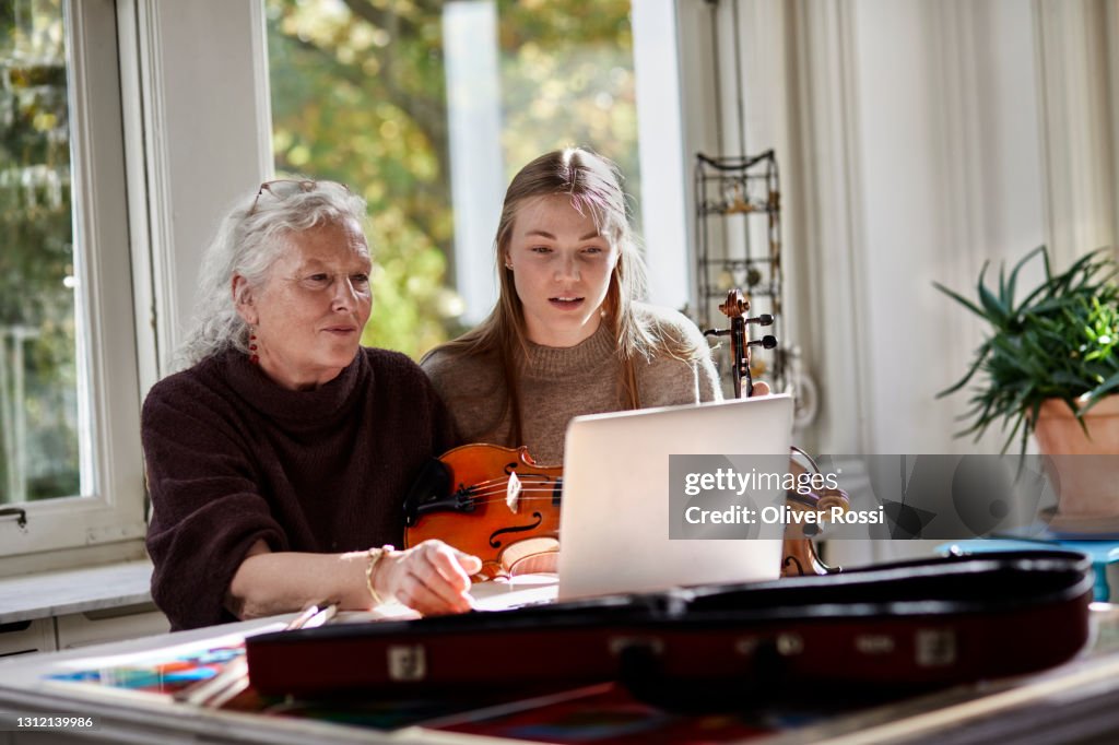 Senior woman and young woman with violin and laptop at home