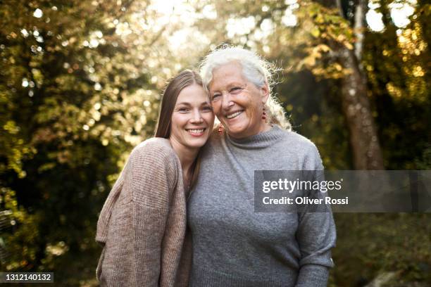 portrait of happy grandmother and adult granddaughter in garden - granny stockfoto's en -beelden