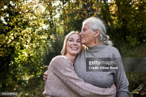 grandmother and adult granddaughter embracing in garden - care stock-fotos und bilder