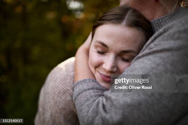 grandmother embracing adult granddaughter in garden - embracing stock-fotos und bilder