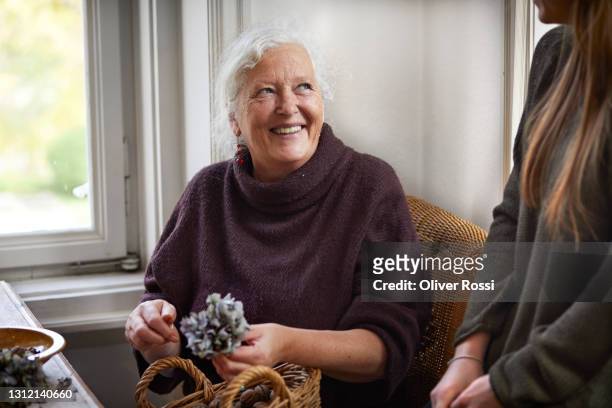 happy senior woman making flower arrangement at home - grandma cane stock pictures, royalty-free photos & images