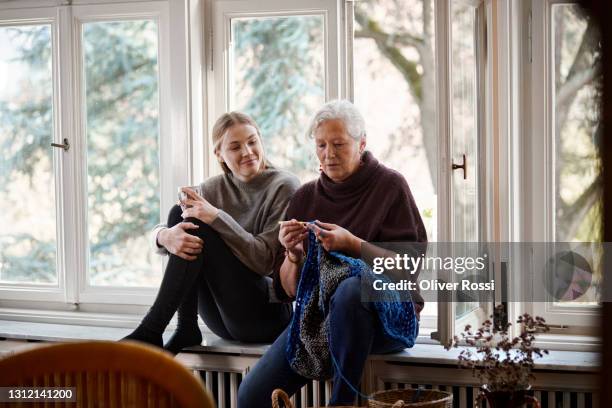 granddaughter watching senior woman knitting on windowsill - old granny knitting stock pictures, royalty-free photos & images