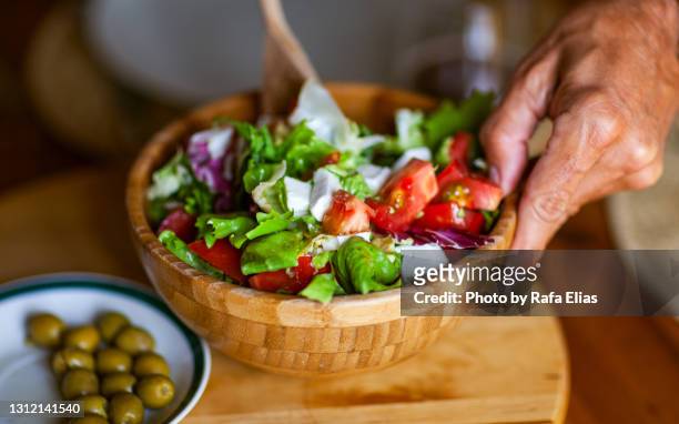 green salad in wooden bowl with lettuce, lombardy, tomato and farmer cheese - stirring stock pictures, royalty-free photos & images