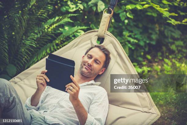 smart working, uomo con tablet in giardino - hammock foto e immagini stock