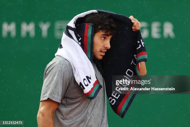 Cristian Garin of Chile takes shelter under a towel as rain falls in his Singles Match against Felix Auger Aliassime of Canada during the First Round...