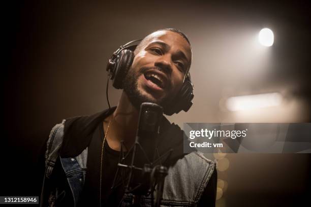 african american musician singing on professional microphone in recording studio. - black singer stock pictures, royalty-free photos & images