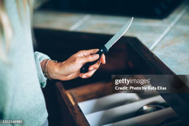 female hand holding a knife in the kitchen - messencriminaliteit stockfoto's en -beelden