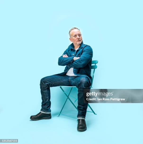 middle-aged man sitting on chair in studio - chairs in studio stock pictures, royalty-free photos & images