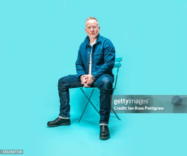 middle-aged man sitting on chair in studio - full length portrait stock pictures, royalty-free photos & images