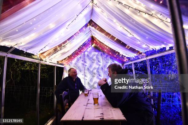 People enjoy a drink in a miniature greenhouse at Harrington Arms pub on April 12, 2021 in Macclesfield, England. England has taken a significant...
