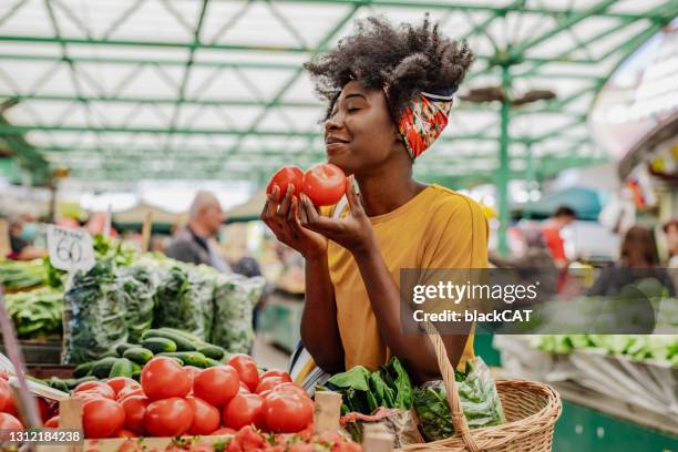 junge afrikanerin kauft tomaten auf dem markt - gemüseladen stock-fotos und bilder