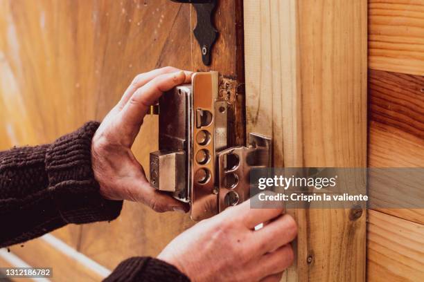 man's hands fixing a lock on a wooden door - commercial door repair stock pictures, royalty-free photos & images