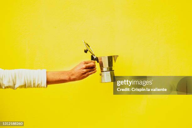 woman hand holding italian coffee pot with lid open with yellow background - koffiepot stockfoto's en -beelden