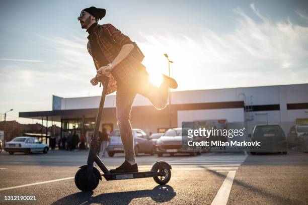 a young man on his e-scooter. technology, ecological concept of mobility. a hipster young man riding an electric scooter. - mobility scooters stock pictures, royalty-free photos & images