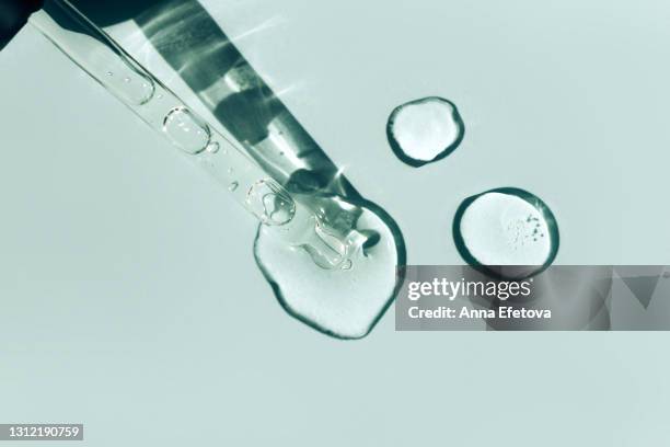 glass pipette with cosmetic liquid with air bubbles leaves puddles on pastel blue background. flat lay style and close-up - blue glass bottle bildbanksfoton och bilder