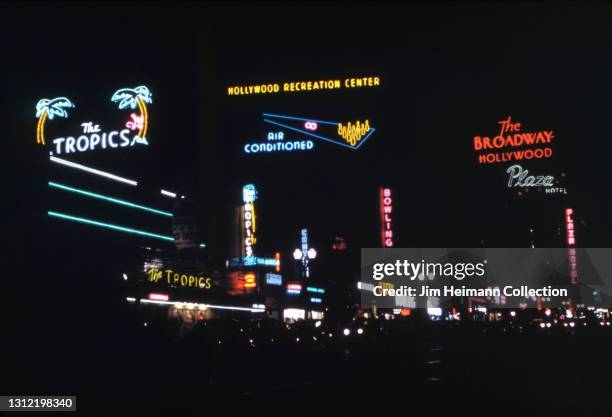 35mm film photo shows Vine Street at night with neon lights for The Tropics, Hollywood Recreation Center, and the Plaza Hotel, 1942.