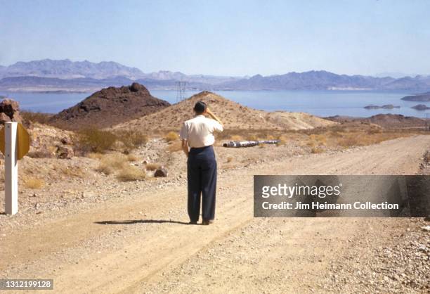 35mm film photo shows a man standing on a dirt road leading to Lake Mead. He looks off towards the water, perhaps estimating how long it might take...