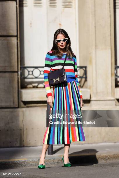 Therese Hellström @tesshell wears white cat-eye sunglasses, a multi colored striped wool midi dress with long sleeves, a brown leather Hermes bag,...