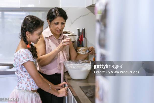 ethnic mother and preteen daughter baking together - indian mother and child stock pictures, royalty-free photos & images