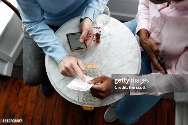 two men look at a bill in a cafe and divide payment with mobile application, shot from above - dividere foto e immagini stock