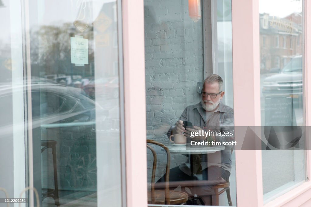 View through window at a man in a cafe drinking coffee