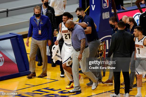 Jamal Murray of the Denver Nuggets is helped off the court after an injury in their game against the Golden State Warriors at Chase Center on April...