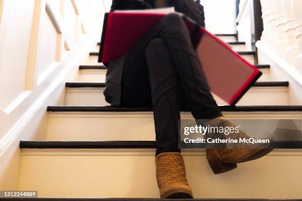 mixed-race teen female student reading while sitting on steps - girls in leggings stock-fotos und bilder