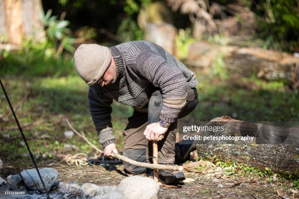 A man making a fire with a bow drill