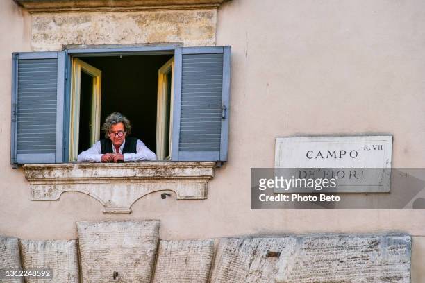een mens kijkt uit een venster in campo de fiori vierkant in het hart van rome - campo de fiori stockfoto's en -beelden