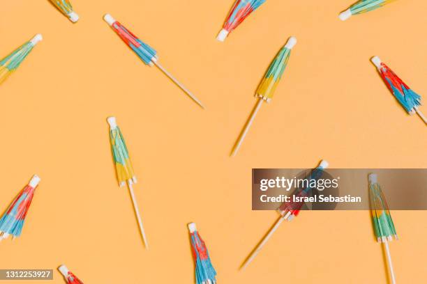 from above of a creative colorful cocktail paper closed umbrella pattern with soft shadows on a yellow background. - cocktail umbrella stock pictures, royalty-free photos & images