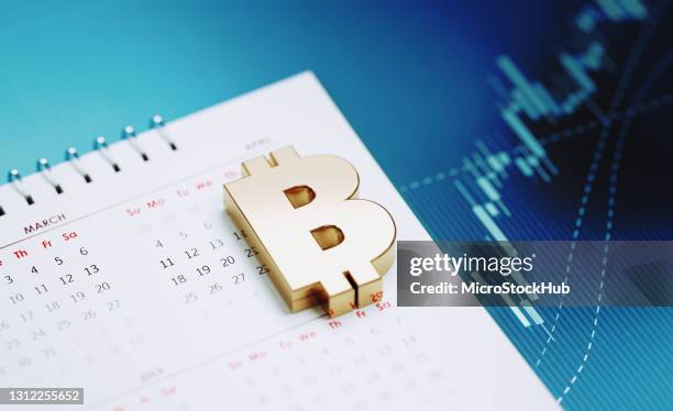 investment and financial planning concept - bitcoin symbol sitting over white calendar on blue financial graph background - financial hub stock pictures, royalty-free photos & images