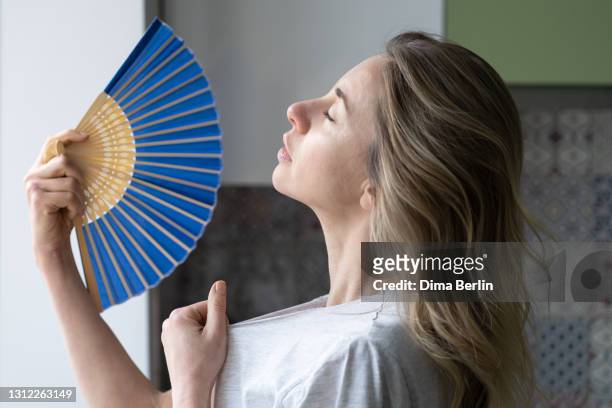 tired overheated woman using wave fan suffer from heat sweating, cools herself,  feels sluggish - calor fotografías e imágenes de stock