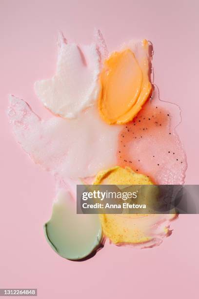 set of textured smears of cosmetic products. herbal green cream, yellow scrub with exfoliating particles, white scrub with coconut oil and sugar, red fruit scrub and orange shower gel on bright pink background. concept of trendy body care procedures of th - coconut white background stock-fotos und bilder
