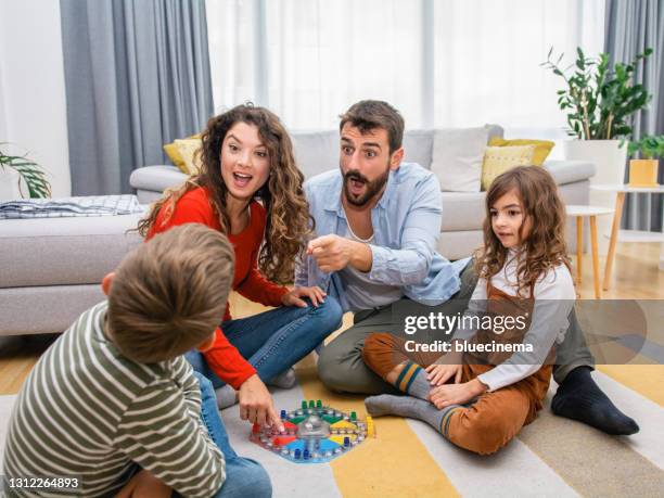 fröhliche eltern spielen brettspiel mit ihren kindern. - spieleabend stock-fotos und bilder