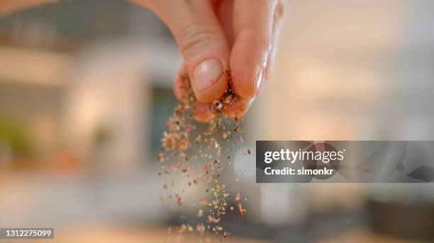 man's hand pouring oregano powder - oregano stock pictures, royalty-free photos & images